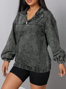 Dettaglio di un pullover in denim grigio effetto lavaggio acido con mezza zip e polsini.