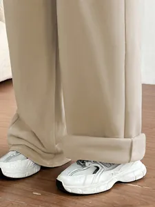 Gros plan détaillé d'un pantalon large kaki avec revers et baskets blanches tendance
