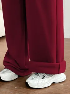 Vue détaillée de l'ourlet du pantalon large rouge foncé avec des baskets blanches