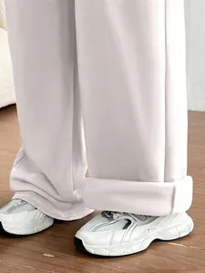 Détail d'un pantalon de jogging blanc cassé à jambes larges avec des baskets blanches
