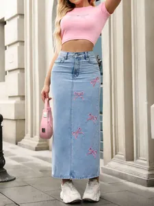 Detailed view of a light blue denim maxi skirt featuring sweet pink embroidered bows