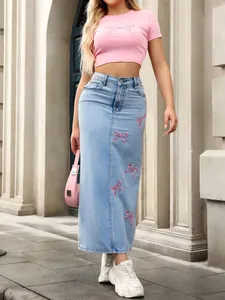 Long light blue denim skirt featuring delicate pink bow embroidery and a high waist.
