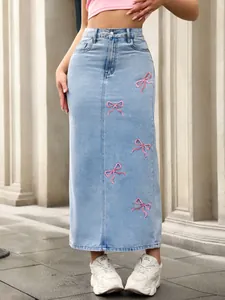 Detailed view of pink embroidered bow patterns on a high-waisted light blue denim skirt