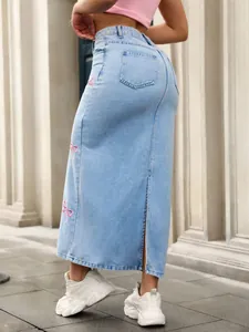 Detail of a light blue denim maxi skirt with pink bow embroidery and back slit detail