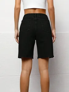 Back view of women's black washed denim Bermuda shorts with raw hem and pockets.