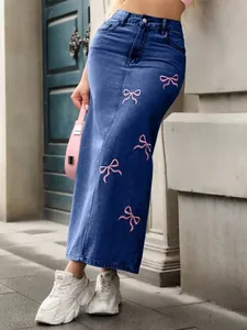 Detailed view of a long denim skirt featuring delicate pink embroidered bow patterns.