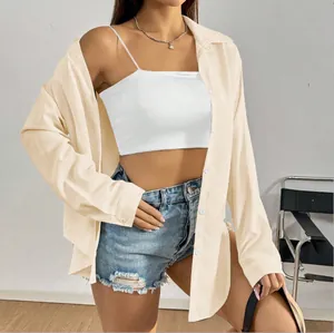 Détail d'une chemise beige à manches longues boutonnée portée avec un haut blanc et un short