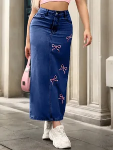 Detail view of pink bow embroidery on high-waist denim maxi skirt.
