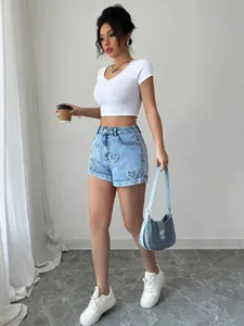 Foto a figura intera di modella con pantaloncini di jeans blu a cuore e crop top bianco