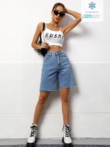 Detailed view of women's loose washed denim bermuda shorts styled with a white crop top