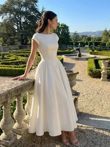 Elegant white satin midi dress with round neck and short sleeves in a lush garden setting.