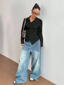 Elegante camicia avvolgente asimmetrica nera con colletto a rever e vita stretta da donna.