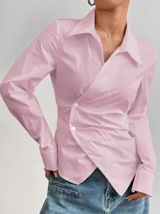 Dettaglio ravvicinato camicia rosa asimmetrica avvitata con bottoni bianchi decorativi.