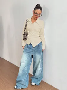 Vista styling di una blusa crema asimmetrica sciancrata con jeans larghi e borsa