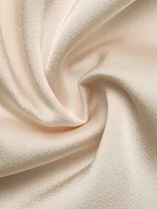 Macro view of elegant champagne satin fabric showing soft texture and luxurious sheen
