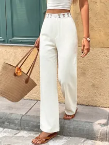 Dettaglio del pizzo traforato su pantaloni bianchi a gamba larga per un look estivo chic