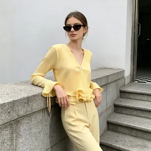 Detailed view of an elegant yellow pleated blouse featuring stylish ruffled bell sleeves.