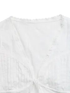 Detailopname van een witte damesblouse met V-hals, kanten rand en jacquard textuur