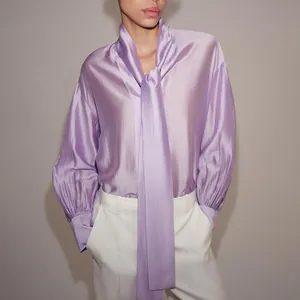 Elegante blusa de satén lavanda con lazo en el cuello en entorno de estudio
