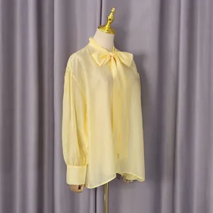 Elegante blusa de color amarillo claro con lazo y mangas abullonadas en maniquí