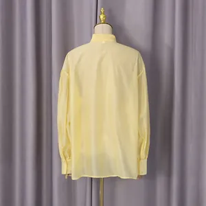 Detalle de la vista posterior de una camisa de manga larga amarilla ligera para mujer en percha