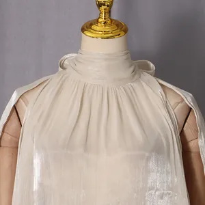 Detailansicht des eleganten, schimmernden Plissee-Stoffes eines hochgeschlossenen Damen-Tops