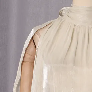 Nahaufnahme einer eleganten plissierten Stehkragenbluse mit schimmerndem Champagner-Stoff