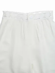 Primo piano del bordo in pizzo floreale e del bottone sulla vita dei pantaloni.