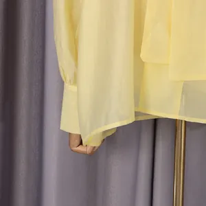 Detalle de la tela amarilla suave y el diseño de los puños de una fresca camisa de verano para mujer