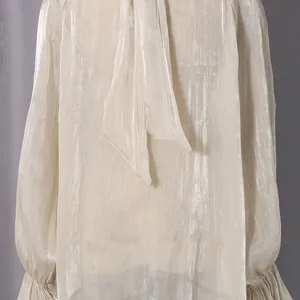 Nahaufnahme einer eleganten, schimmernden Champagner-Bluse mit Schluppe am Hals