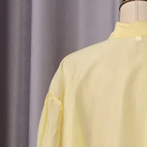 Detalle de cerca de una blusa amarilla que muestra la textura y costuras de hombro