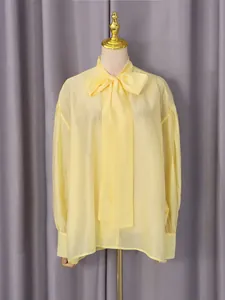 Elegante blusa de manga larga en amarillo claro con cuello de lazo para un look refinado.