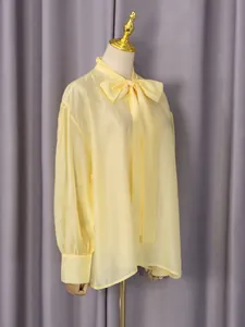 Elegante blusa de manga larga amarillo pálido con lazo en el cuello en maniquí