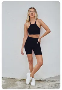 Women's black seamless yoga set with halter sports bra and high-waisted shorts.