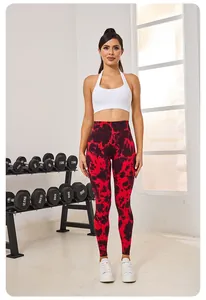 Athlète féminine en legging de fitness tie-dye rouge et brassière de sport blanche au gymnase