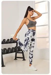 Femme en leggings tie-dye et brassière de sport s'étirant dans un studio de fitness.