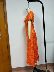 Vista laterale del maxi vestito bohémien arancione stampato su un manichino con motivi fini.