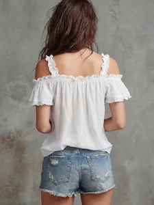 Vista posteriore di un top bianco con spalle scoperte, volant e pantaloncini di jeans.