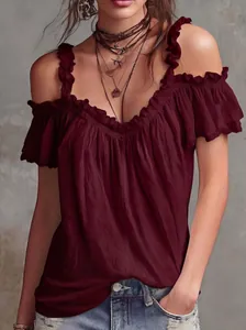 Dettaglio di una blusa bordeaux con spalle scoperte, volant eleganti e tessuto a trama