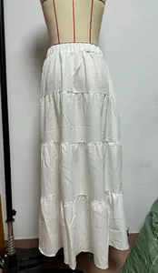 Dettaglio di una gonna lunga bianca a balze su un manichino, vestibilità ampia e casual.