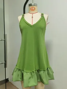 Dettaglio di un mini abito verde smanicato con scollo a V e bordo a balze su manichino