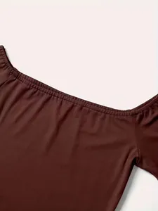 Dettaglio ravvicinato della scollatura elastica a spalle scoperte su un top marrone alla moda