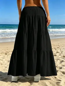Vista posteriore di una gonna lunga nera a balze casual su una spiaggia assolata.