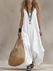 Bohemian white sleeveless maxi dress detail showing flowing linen fabric and straw bag