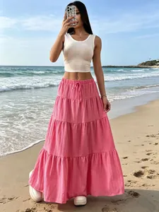 Gonna lunga bohémien rosa a balze pieghettate da donna in una scena estiva in spiaggia