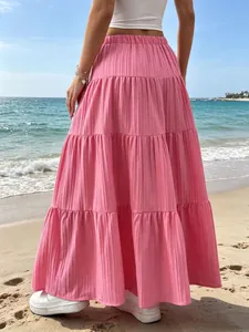 Dettaglio di una gonna lunga rosa a balze per donna vista da dietro su una spiaggia.