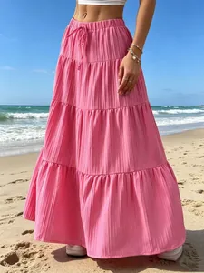 Vista dettagliata della gonna lunga rosa a balze con trama plissettata sulla spiaggia