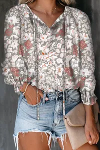 Close-up detail of women's pink floral long sleeve blouse featuring a stylish V-neck and tie