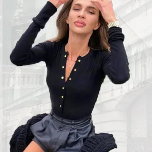 Woman wearing a slim fit black long-sleeve ribbed bodysuit with decorative gold buttons