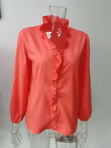 Dettaglio del colletto a balze e della patta di una camicia corallo a maniche lunghe.